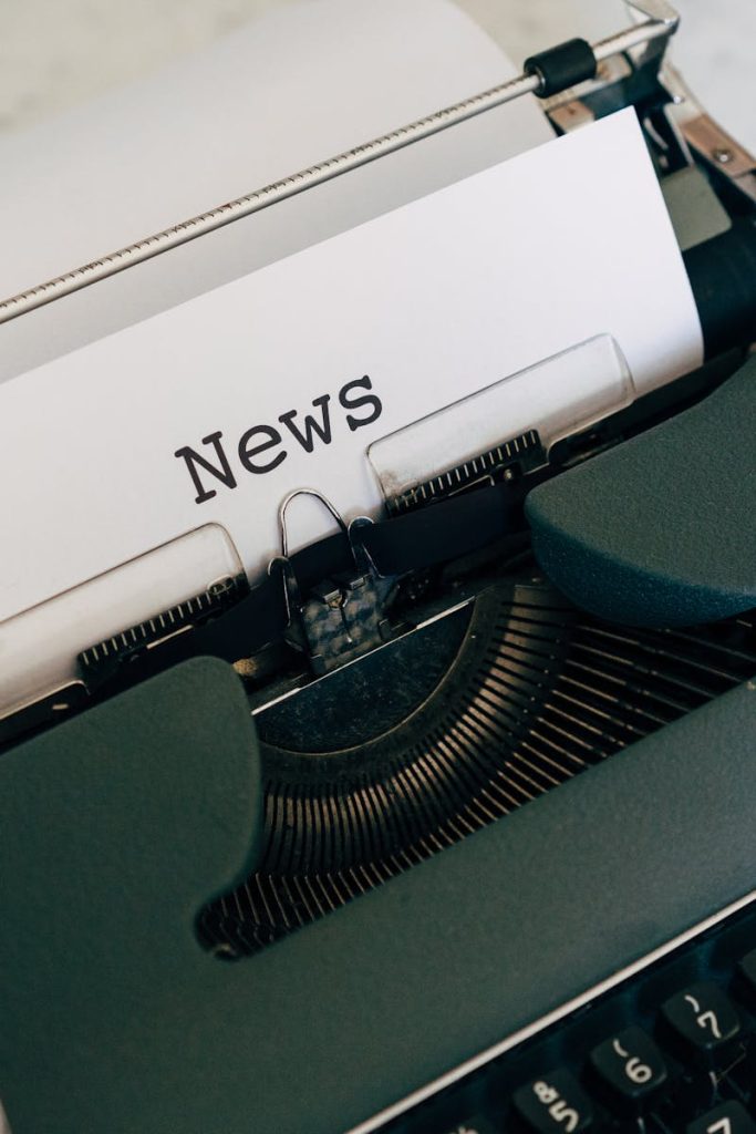 Close-up of an antique typewriter with 'News' on paper.